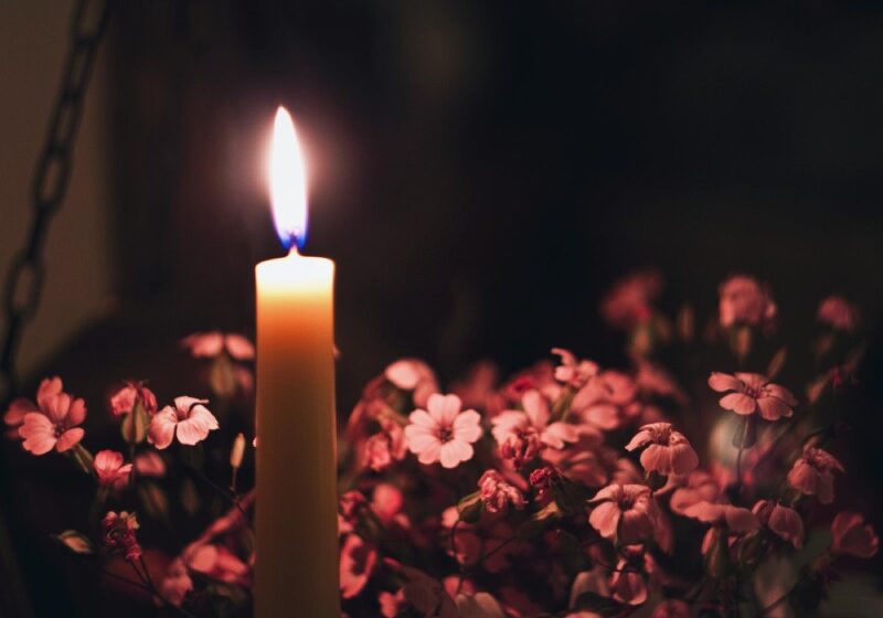 Close-up of lit candle by flowers